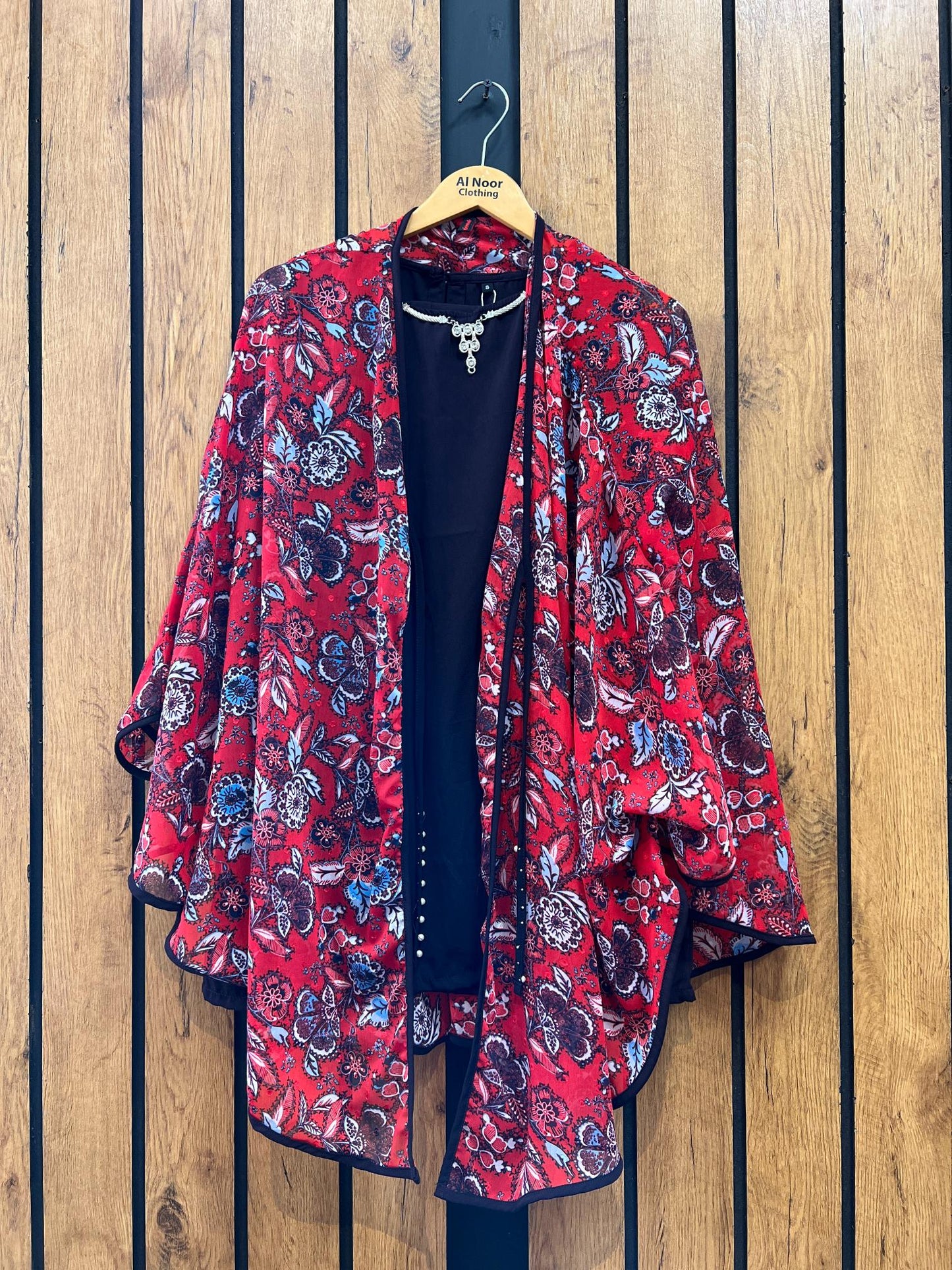 Red floral women's kimono jacket with black inner top on wooden hanger